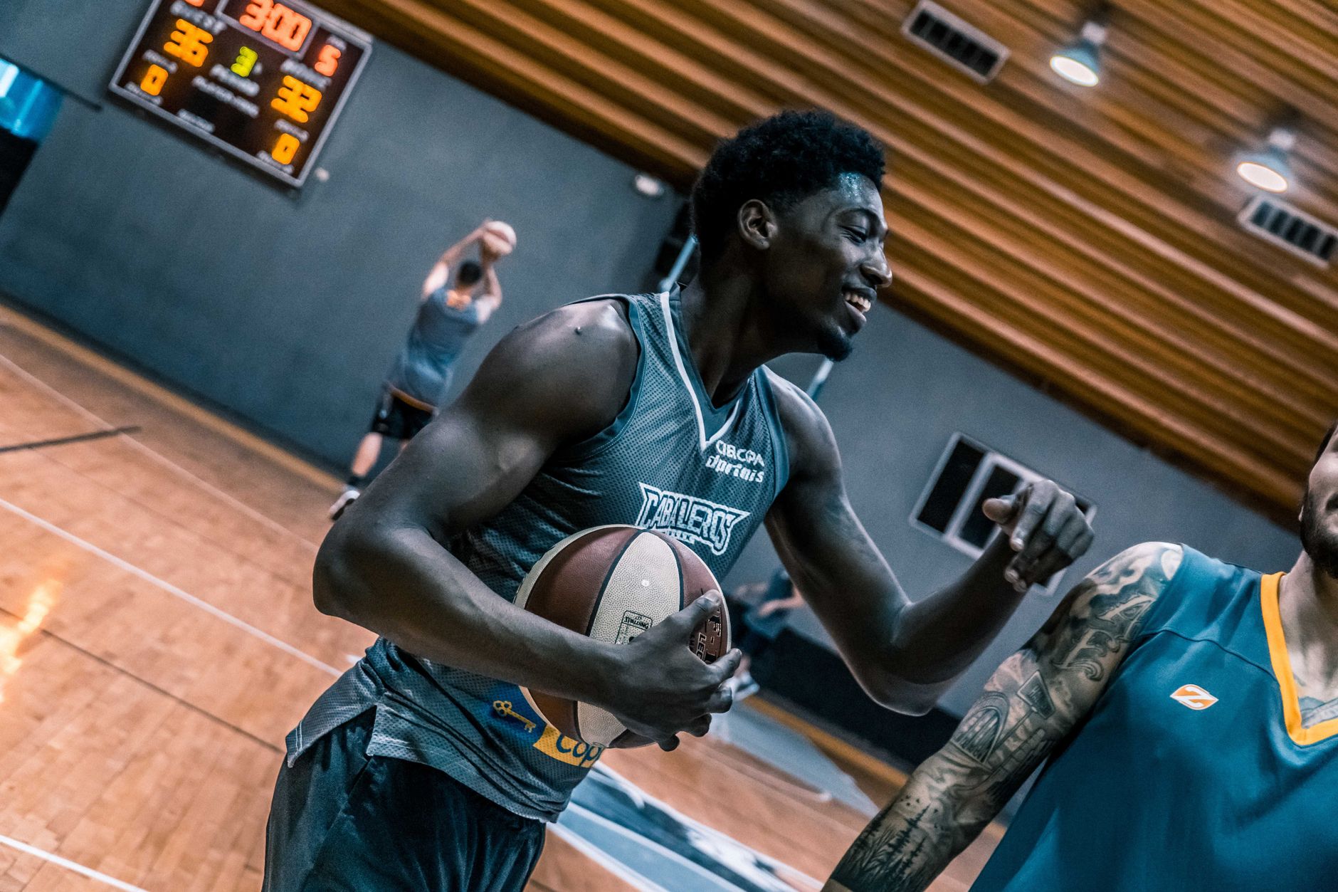 Moment intense de joueurs de basket-ball lors d'une séance d'entraînement en salle sur un terrain en bois.