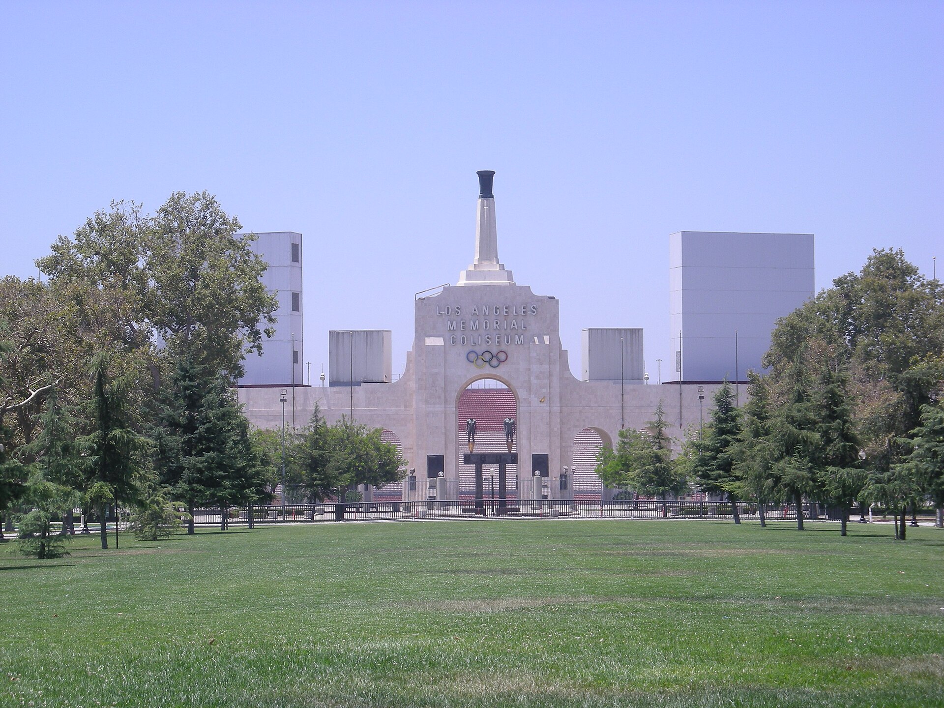 Péristyle d'un stade olympique historique surmonté de sa vasque et des anneaux